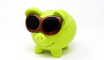 quietschgrünes Sparschwein mit einer Sonnenbrille